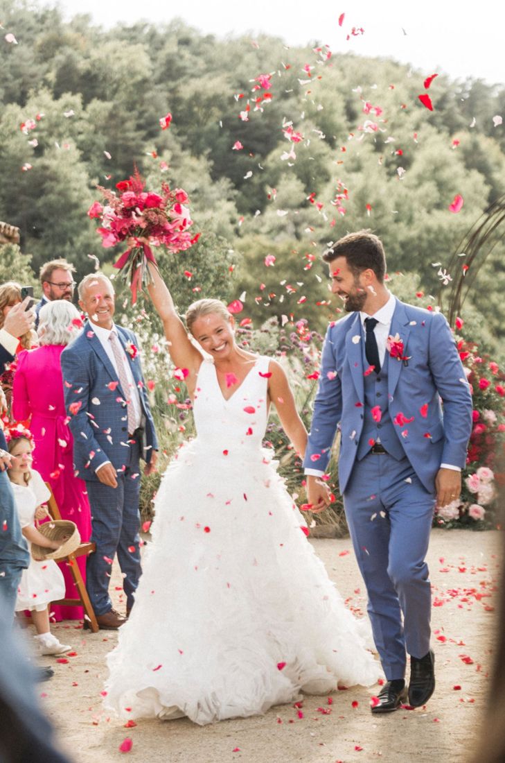 Couple walking through confetti with guests cheering