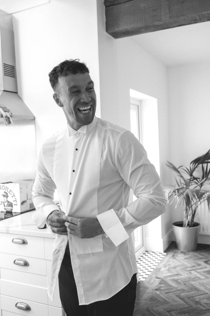 Groom laughing as he gets ready